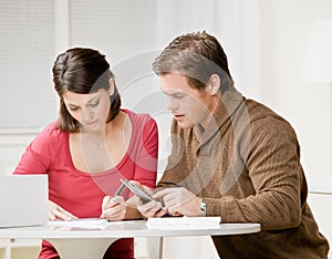 Couple using calculator to pay monthly bills