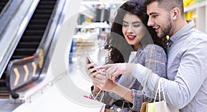 Couple using cellphone, shopping in city mall