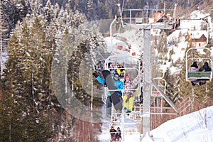 Couple using chairlift at mountain ski resort. Winter