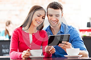 Couple using digital tablet in cafe