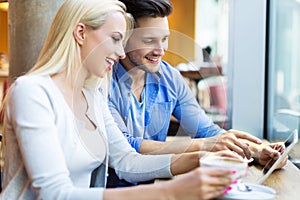 Couple using digital tablet at cafe