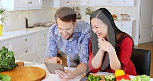Couple using digital tablet in kitchen at home 4k