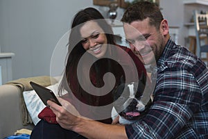 Couple using digital tablet with their pet dog in living room