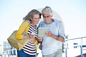 Couple using digital tablet on walkway