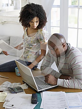 Couple Using Laptop With Bills