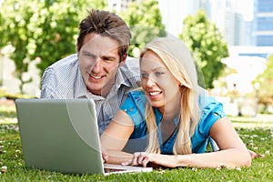 Couple using laptop in city park