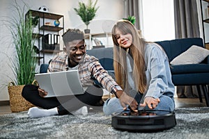 Couple using laptop for controlling robot vacuum cleaner