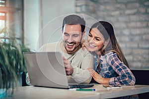 Couple Using Laptop On Desk At Home