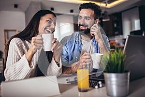 Couple using a laptop and digital tablet together working at home