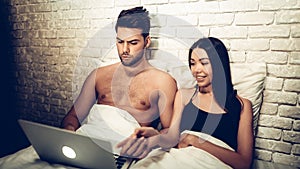 Couple Using Laptop Lying on Bed Watching Movie