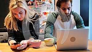 Couple using laptop and mobile phone in kitchen 4k