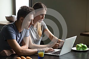 Couple using laptop for reading news or work having breakfast