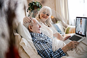 Couple using laptop while sitting on the bed