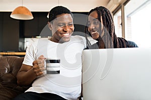 Couple using laptop while sitting on couch at home.