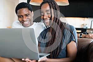 Couple using laptop while sitting on couch at home.