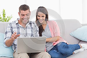 Couple using laptop for video conference on sofa