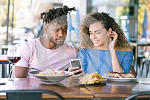 Couple using a mobile phone on a date at a restaurant.