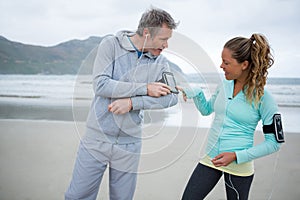 Couple using mobile phone while listening music on beach