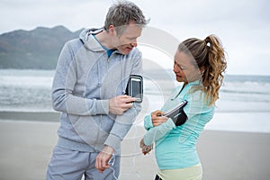 Couple using mobile phone while listening music on beach