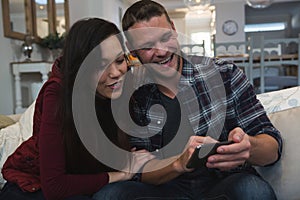 Couple using mobile phone in living room