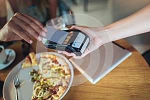 Couple using mobile phone and making contactless payment in a restaurant. S