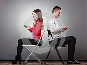 Couple using mobile phones not talking. Conflict.