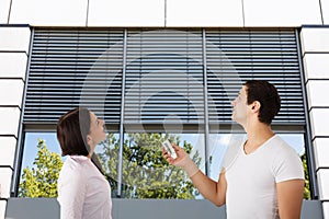 Couple Using Remote To Open Window Shutter