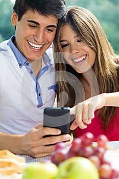 Couple using smart phone on romantic picinic.