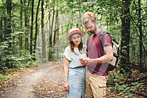 Couple using smart phone to navigate in woods. Theme tourism and navigation, search way, create route, gps phone app. Two people