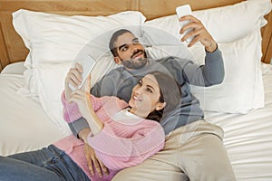 Couple Using Smartphones Lying In Bed In Bedroom, Above View