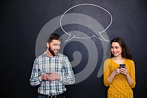 Couple using smartphones over blackboard with speech dialogue