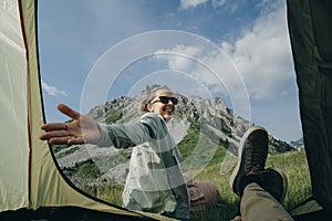 Couple vacationer campers in tent with mountain view in Montenegro. Woman invites to walk photo