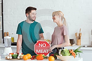 couple of vegans looking at each other with no meat sign
