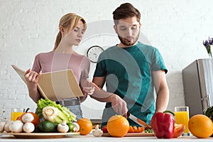 couple of vegans preparing food with recipe book