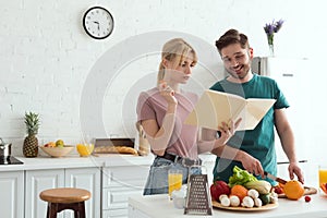 couple of vegans preparing salad with recipe book
