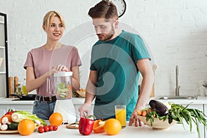 couple of vegans preparing vegetable juice with juicer