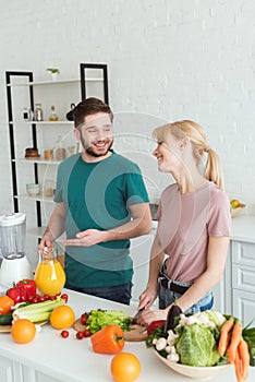 couple of vegans smiling and talking while cooking food