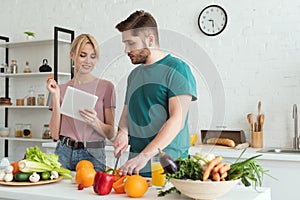 couple of vegans using tablet with recipe for cooking