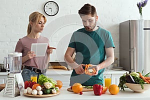 couple of vegetarians using tablet with recipe for cooking