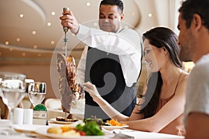 Couple, waiter and serving for dinner in restaurant with meat, happiness and fine dining for anniversary or honeymoon