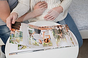 Couple waiting for baby flips through photo book from family  photo shoot