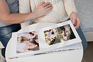 Couple waiting for baby flips through photo book from family  photo shoot