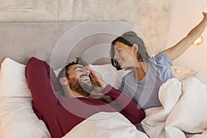 Couple waking up in the morning, yawning and stretching in bed
