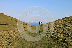A couple walk in a dip in the hills at Seatown in Dorset, situated on the coastal path on the Jurassic coast between Charmouth and photo