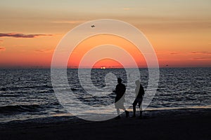 Couple walking along the beach at sunset