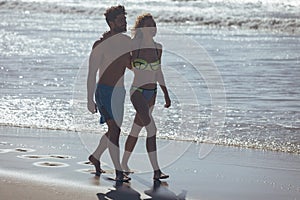 Couple walking with arm around at beach