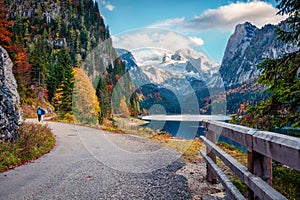 Couple walking around a Vorderer/Gosausee lake. Nise autumn scene of Alps with Dachstein glacier on background. Great morning view