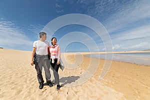 A couple is walking on a beach, enjoying the beautiful view of the ocean