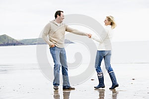 Couple walking on beach holding hands smiling