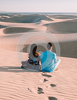 couple walking at the beach of Maspalomas Gran Canaria Spain, men and woman at the sand dunes desert